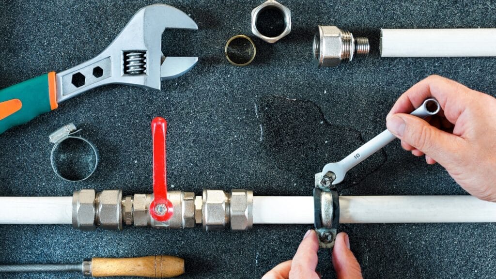 Plumber repairing a pipe valve with an adjustable wrench in Davenport