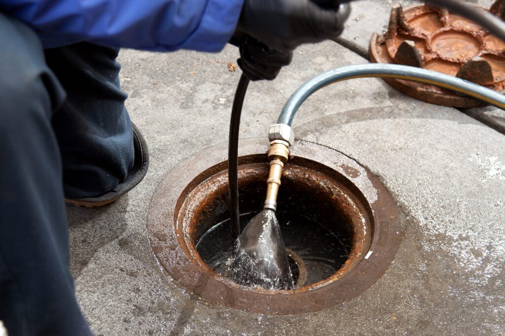 Plumber hydro jetting a sewer line through a manhole in Davenport