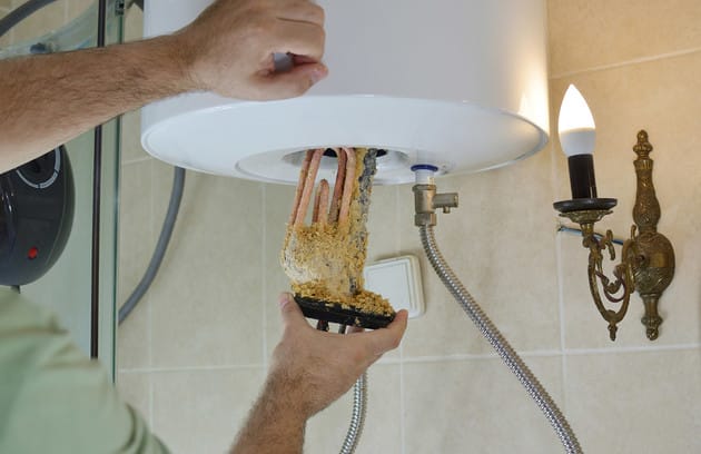 Technician removing mineral buildup from a water heater in Davenport
