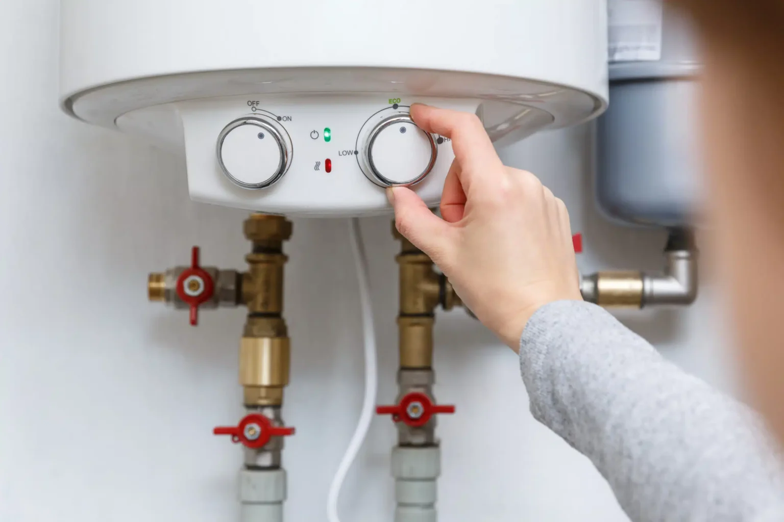 Homeowner adjusting the temperature controls on a water heater in Davenport